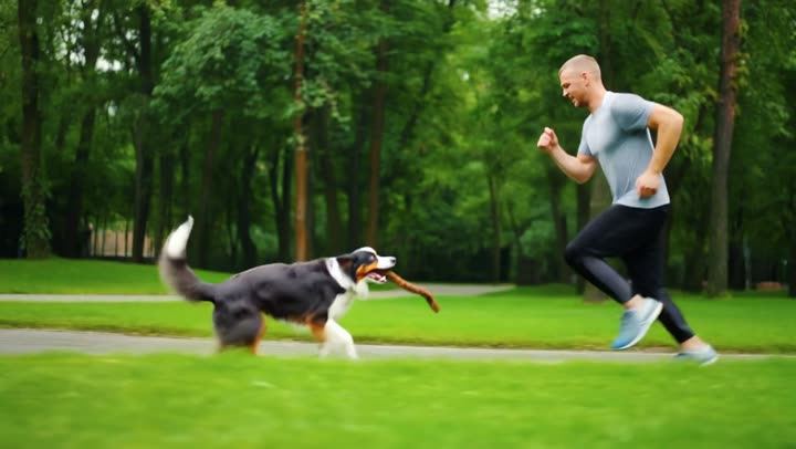 A man running with a dog in a park