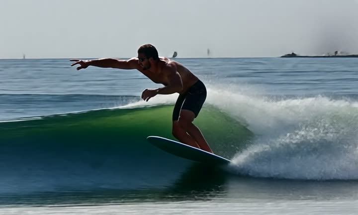 A surfer riding a wave in grey light