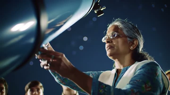 A woman adjusting a telescope at night