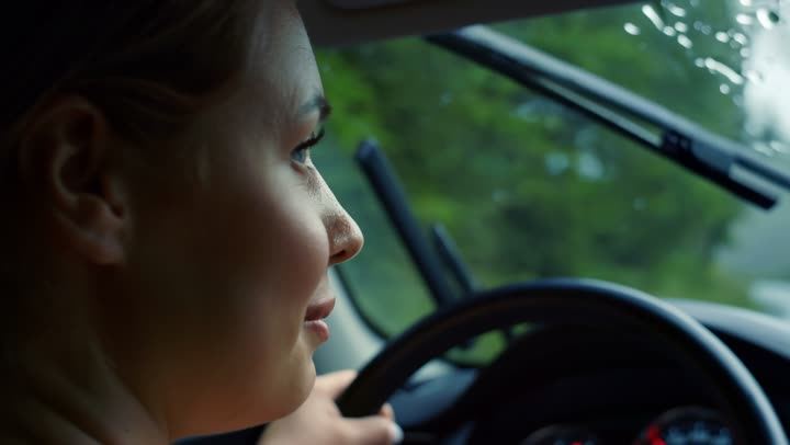 A woman driving, seen through the side window